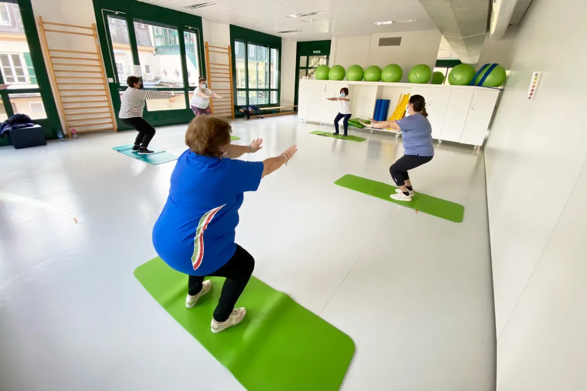 Séance de réhabilitation physique en petit groupe, sur tapis, dans une salle lumineuse de la Clinique La Lignière